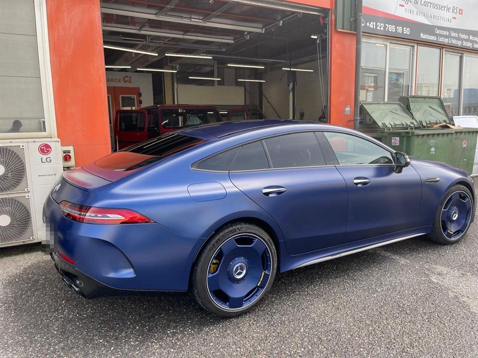 Mercedes-AMG GT 4 portes bleu mat devant l'entrée de l'atelier
